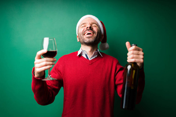 Adoro fare festa! Eccitato uomo latino bere vino rosso a una festa di Natale e divertirsi  - Foto, immagini