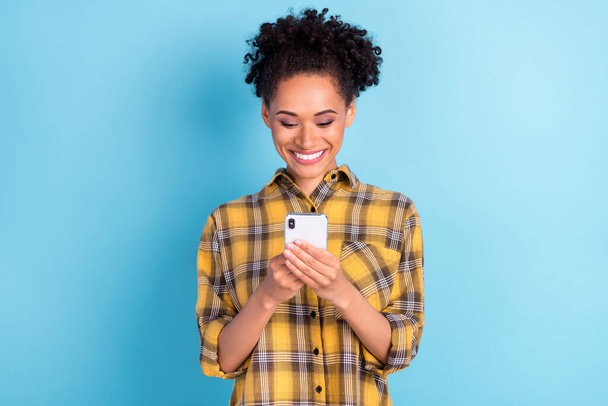 Photo portrait curly woman smiling using cellphone isolated pastel blue color background - Foto, imagen
