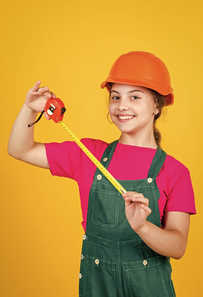 length. construction worker with tape measure. Cute kid as a construction worker. kid repairing home. happy childhood. self-retracting metal tape measure. Little girl using a measuring tape - Photo, Image