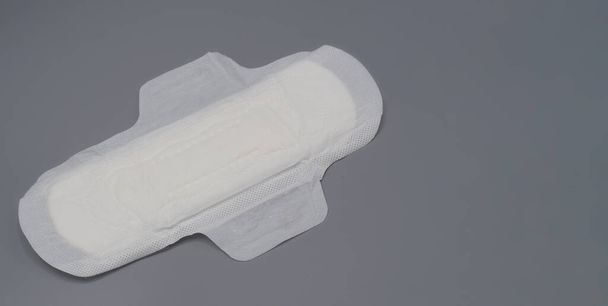 Napkin sanitary. Soft and comfort sanitary napkin pad and grey background. White top sheet. Studio shot isolated. Cloth pads for menstruation. Wing type for night. Quick absorber. cotton soft feeling. - Photo, Image