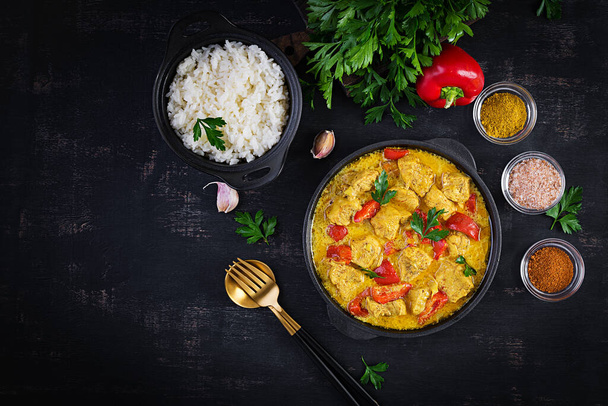 Traditional Indian curry chicken masala. Indian chicken curry with sweet peppers and  rice in bowl, spices, dark background. Traditional Indian dish. Top view, flat lay - Photo, Image