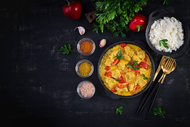 Traditional Indian curry chicken masala. Indian chicken curry with sweet peppers and  rice in bowl, spices, dark background. Traditional Indian dish. Top view, flat lay - Photo, Image