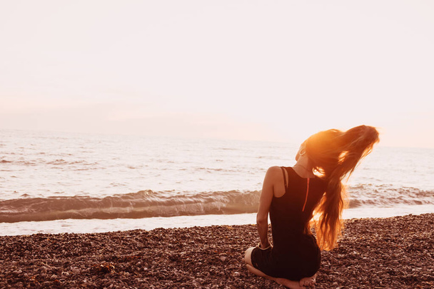 Silhouette egy karcsú lány naplemente háttér. A nap leesik a tenger horizontján. Estét, enyhe szellőt és egy fiatal hölgyet a parton. Rázkódik a haja. Oroszország. Napot. Nyár. - Fotó, kép
