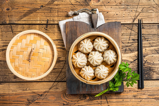 Momo dumplings in a bamboo steamer. Wooden background. Top view - Photo, Image