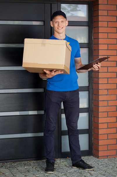 Smiling courier holding cardboard box  - Foto, Imagen