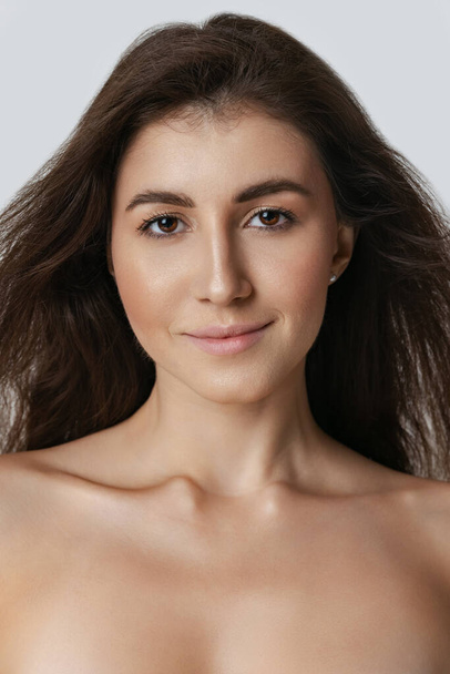 Close-up portrait of young beautiful slim woman without makeup isolated over gray studio background. Natural beauty concept. - Foto, afbeelding