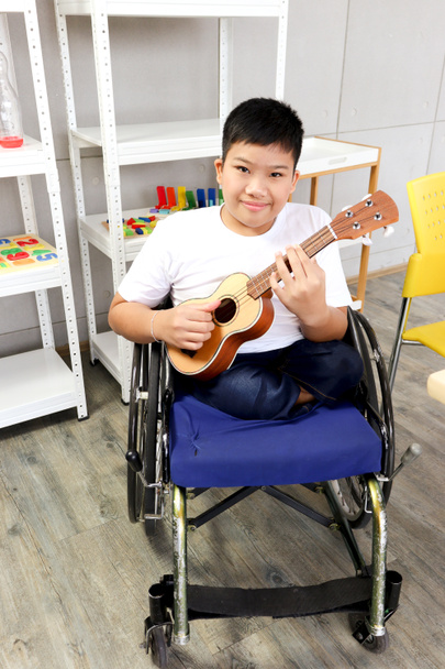 Šťastné dítě baví během studia ve škole, usměvavý chlapec sedí v invalidním vozíku učí hrát ukulele, vzdělávání dítěte s fyzickým postižením konceptu. - Fotografie, Obrázek