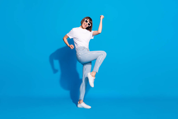 Full length body size photo careless girl in sunglass gesturing like winner isolated bright blue color background - Fotografie, Obrázek