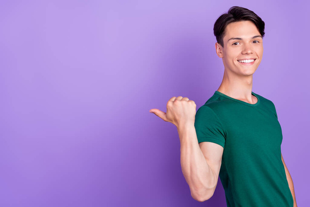 Photo of attractive young happy positive man point finger empty space sale news isolated on purple color background - Zdjęcie, obraz