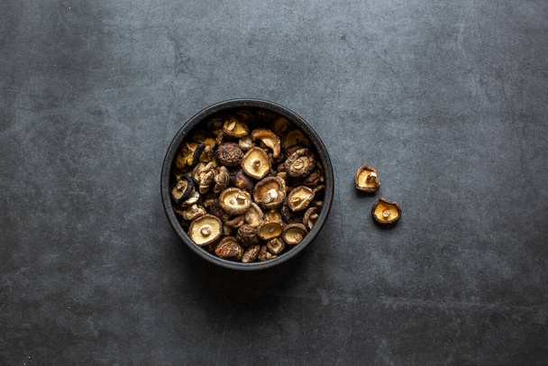 Dried Shiitake Mushrooms in bowl on dark grey background. - Fotó, kép