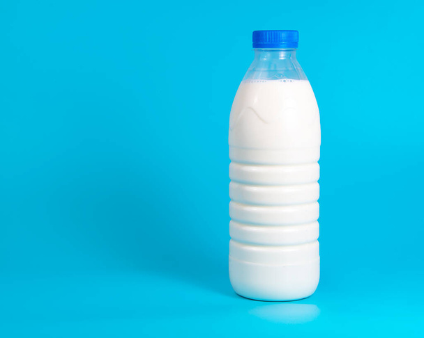 Natural white milk in plastic bottle on blue background with copyspace selective focus - Foto, Imagen