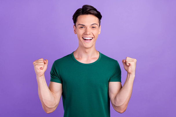 Photo of amazed young happy man raise fists winner celebrate enjoy isolated on purple color background - Photo, image