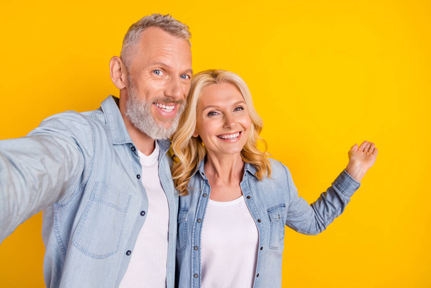 Photo of cheerful happy old couple spouses make selfie hand empty space isolated on yellow color background - Fotoğraf, Görsel