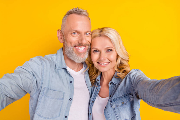 Photo of old couple wife husband make selfie good mood smile enjoy cool isolated on yellow color background - Foto, Imagen
