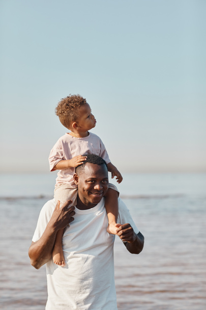アフリカ系アメリカ人の父親が赤ちゃんを肩に担いで - 写真・画像