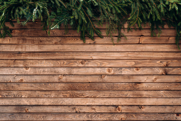Стена деревянного забора. Зимний деревянный фон, коричневые горизонтальные доски, текстура дерева, забор и елки бранчи. Фото на складе - Фото, изображение