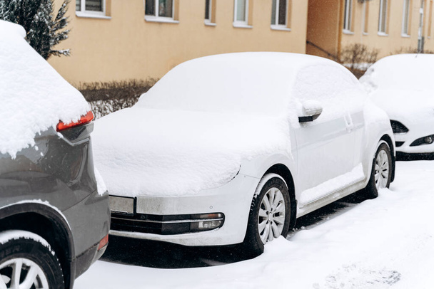 Volle Sicht auf die Autos nach dem Schneesturm. Reihen von Autos stehen auf einer schneebedeckten Straße. Winterkonzept  - Foto, Bild