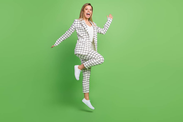 Full size photo of amazed nice positive woman jump up good mood enjoy isolated on green color background - 写真・画像
