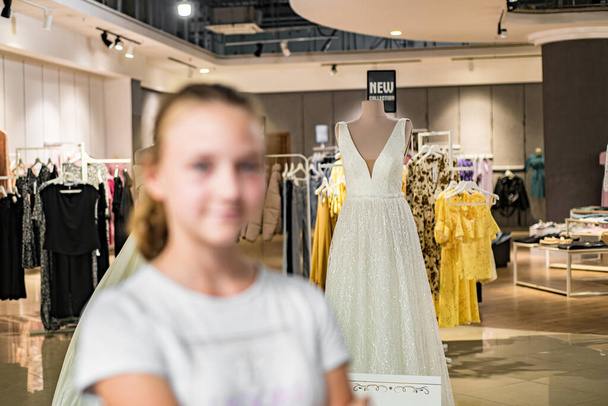 Mädchen auf dem Hintergrund eines weißen Kleides, eine neue Kollektion in einem Hochzeitssalon. - Foto, Bild