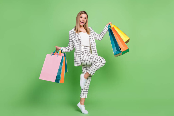 Full length photo of cheerful young woman hold hands bags sale shopping center isolated on green color background - Photo, Image