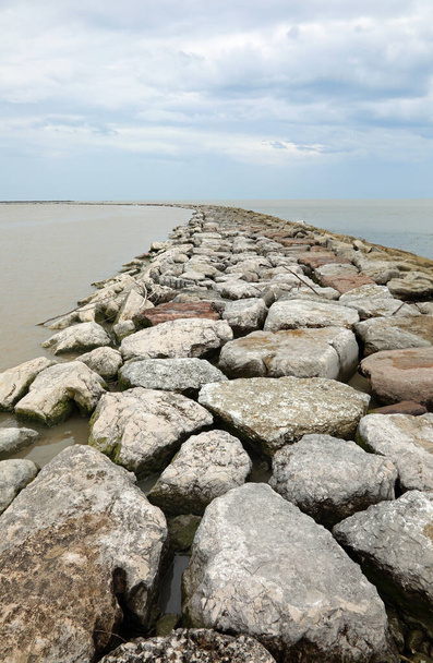 Boca del río ADIGE con los terraplenes hechos de piedras grandes y el mar Adriático en el fondo en el norte de Italia - Foto, Imagen