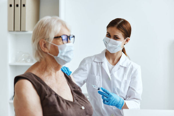 sairaanhoitaja valkoisessa takissa iäkkään naisen rokottaminen terveydenhuolto - Valokuva, kuva