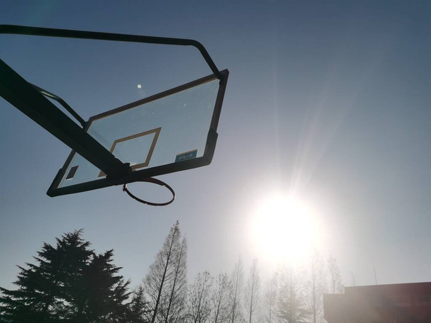 a low angle shot of a basketball hoop on a background of a snowy road - Фото, зображення