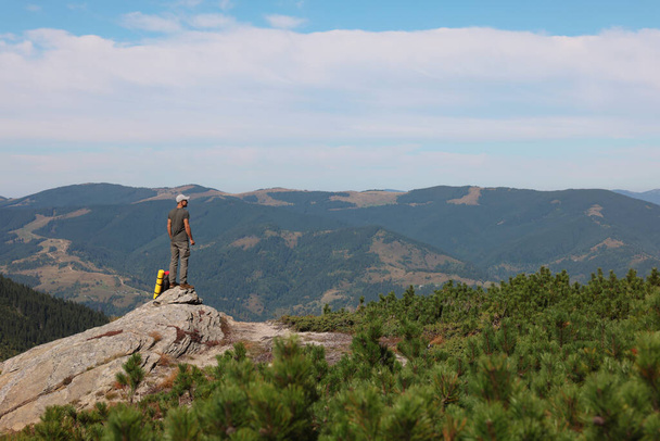 Man with backpack on rocky peak in mountains, back view - Fotó, kép
