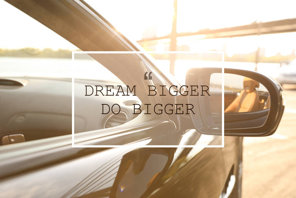 Dream Bigger Do Bigger. Inspirational quote motivating to set life goals freely and forget about reasons that can hold back. Text against luxury car, closeup - Foto, Imagen