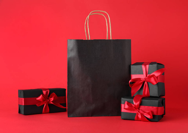 Gift boxes and shopping bag on red background. Black Friday sale - Foto, Imagen