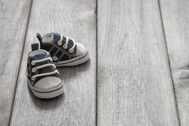 little baby sneakers on wooden background, cute small shoes on old wooden floor, the concept of the first steps of a baby, 1 year old - Photo, image