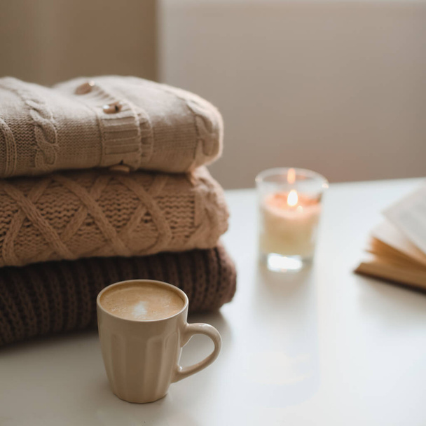 cozy comfortable home autumn still life with a candle, book, knitted sweaters and plaid - Fotografie, Obrázek