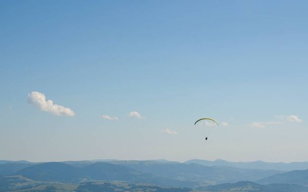 Paraglider letící nad Karpatskými horami proti jasnému nebi v letním dni - Fotografie, Obrázek