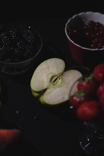 黒暗色の背景、果実、バナナ、リンゴ、ラズベリー、クランベリーで一緒に異なる果物 - 写真・画像
