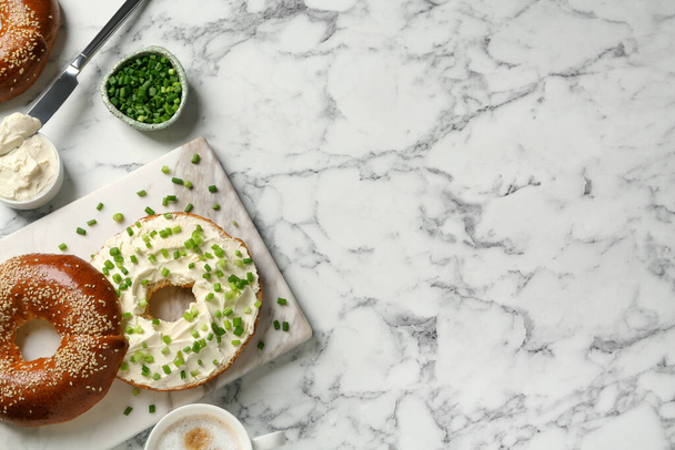 Delicious bagel with cream cheese and green onion on white marble table, flat lay. Space for text - Foto, immagini