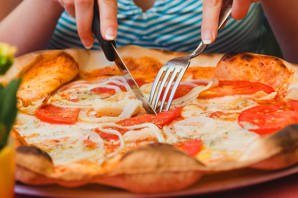 kobieta zje pizzę. bliska pomidorów i sera włoskiej pizzy z widelcem i nożem - Zdjęcie, obraz