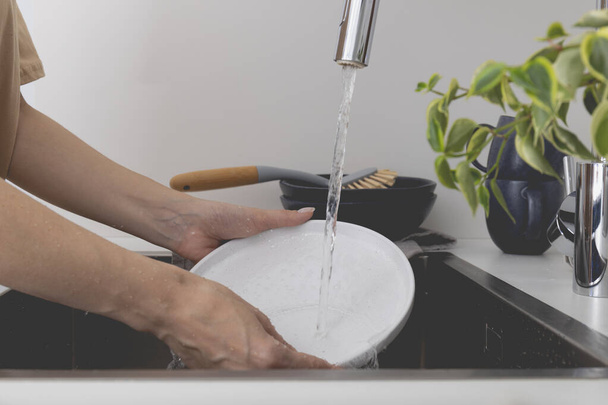 Kobieta zmywa naczynia w zlewie, widok z bliska. Sprzątanie. Wysokiej jakości zdjęcie - Zdjęcie, obraz