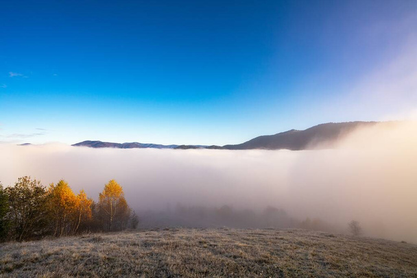 Sunrise over mountain hils covered with gray mist. - 写真・画像
