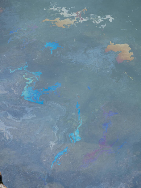 Βρώμικο ελαιώδες φιλμ στην επιφάνεια της γαλαζοπράσινης θάλασσας στην παραλία. βιομηχανική απόρριψη λυμάτων διαρροή .Λάδι ταινία ρύπανση. Πολύχρωμο φιλμ λαδιού στο νερό. βιομηχανική διαρροή υγρών αποβλήτων. ουράνιο τόξο στη θάλασσα - Φωτογραφία, εικόνα