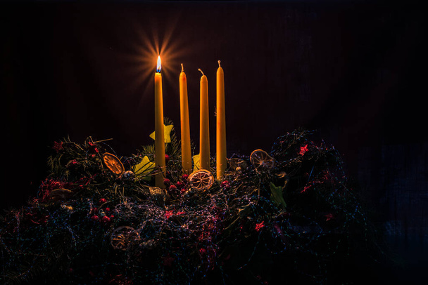 1 świeca świeca na kolorowe dekorowane wieniec adwentowy z czterech świec na czarnym tle - Zdjęcie, obraz