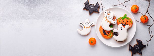 Halloween gingerbread cookies on white plate on stone background. Bright homemade cookies for Halloween party. Copy space - Photo, image