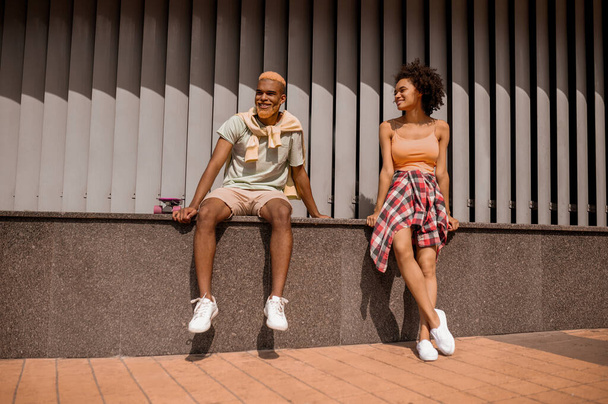Фото молодой темнокожей пары, говорящей и выглядящей вовлеченной - Фото, изображение