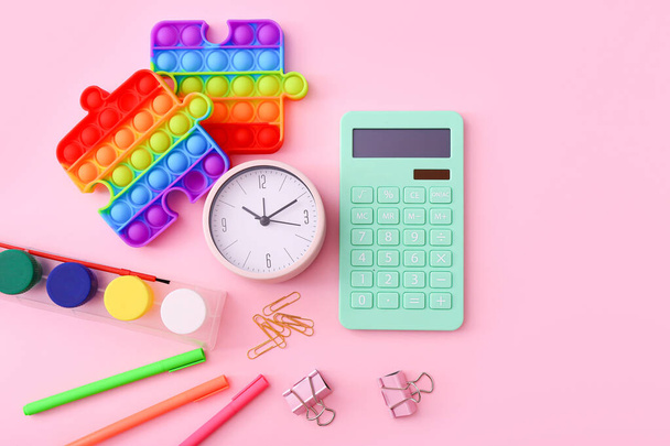 Flat lay of stationery, clock and silicone toys popit on pink background - Photo, Image