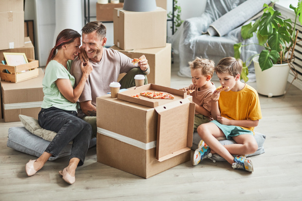 Happy Family Eating Pizza in New Home - Zdjęcie, obraz