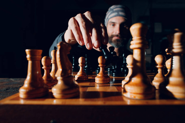 Nuori aikuinen komea mies pelaa shakkia pimeässä puolella valaistu - Valokuva, kuva