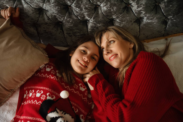 hija y madre en suéteres de Navidad cerca del árbol de Navidad en casa - Foto, Imagen