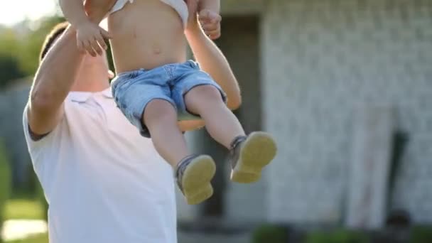 Счастливый мальчик с синдромом Дауна играет со своим отцом на улице. Отец бросает ребёнка в объятия - Кадры, видео