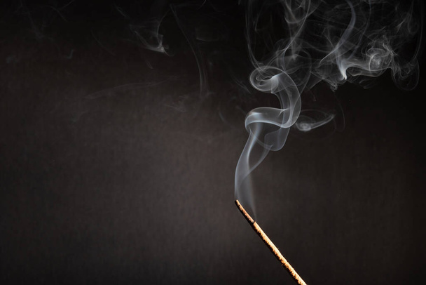 Bâton d'encens avec fumée sur fond noir
 - Photo, image