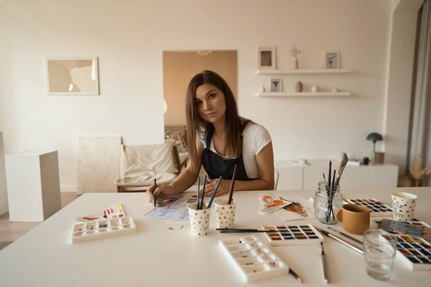 Beautiful Female Artist In Her Studio. Female drawing in album with watercolor paints and paintbrush. - Foto, immagini