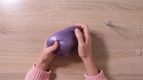 Slime DIY. Female Hands sprinkle glitter on the slime. 4k resolution video. Close up and top view of female hand holding purple shining slime and squeezing it. - Footage, Video